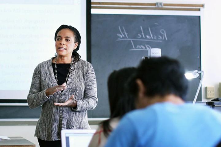 Professor teaching room of students in front of blackboard